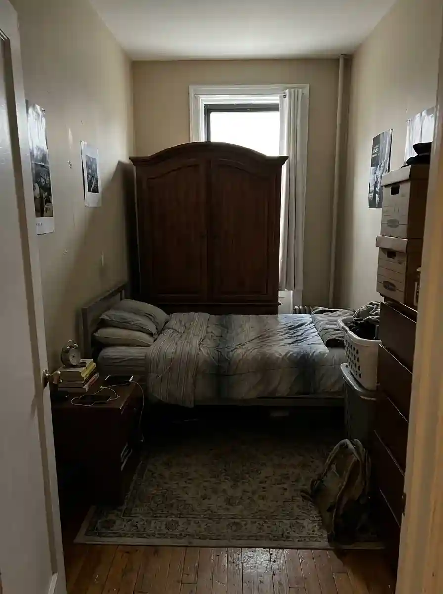 Small bedroom with blocked window light caused by tall furniture, visually cramped atmosphere, realistic apartment layout