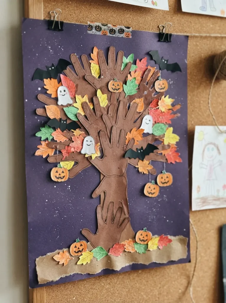 ![Halloween handprint tree craft with brown paper branches, colorful leaves, paper bats, pumpkins, and ghosts, created by children on dark purple construction paper, vertical Pinterest photography.]